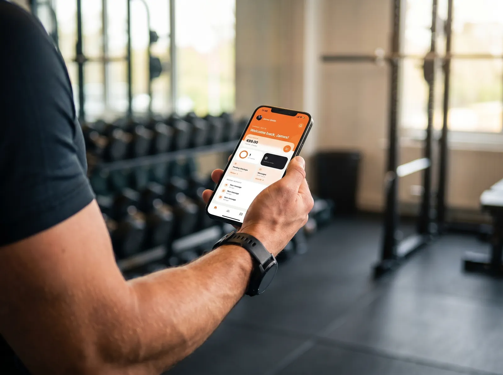 Trainer in a gym holding a phone showing the Scraler client app home screen